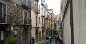 Une rue étroite bordée de bâtiments historiques, dont certains sont dotés de balcons et de portes en arc de cercle.
