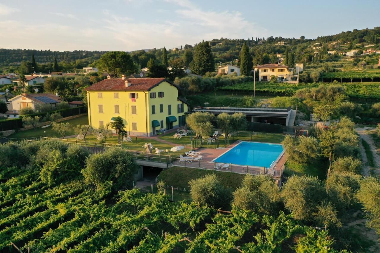 Ein großes, gelbes Gebäude mit Swimmingpool und einem Weinberg im Vordergrund.