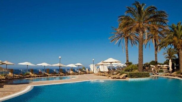 A pool with lounge chairs and umbrellas, surrounded by palm trees. - Apartment Two Weeks Right of Use at Radisson Blu Resort & Spa, Golden Sands (L/o Mellieha)