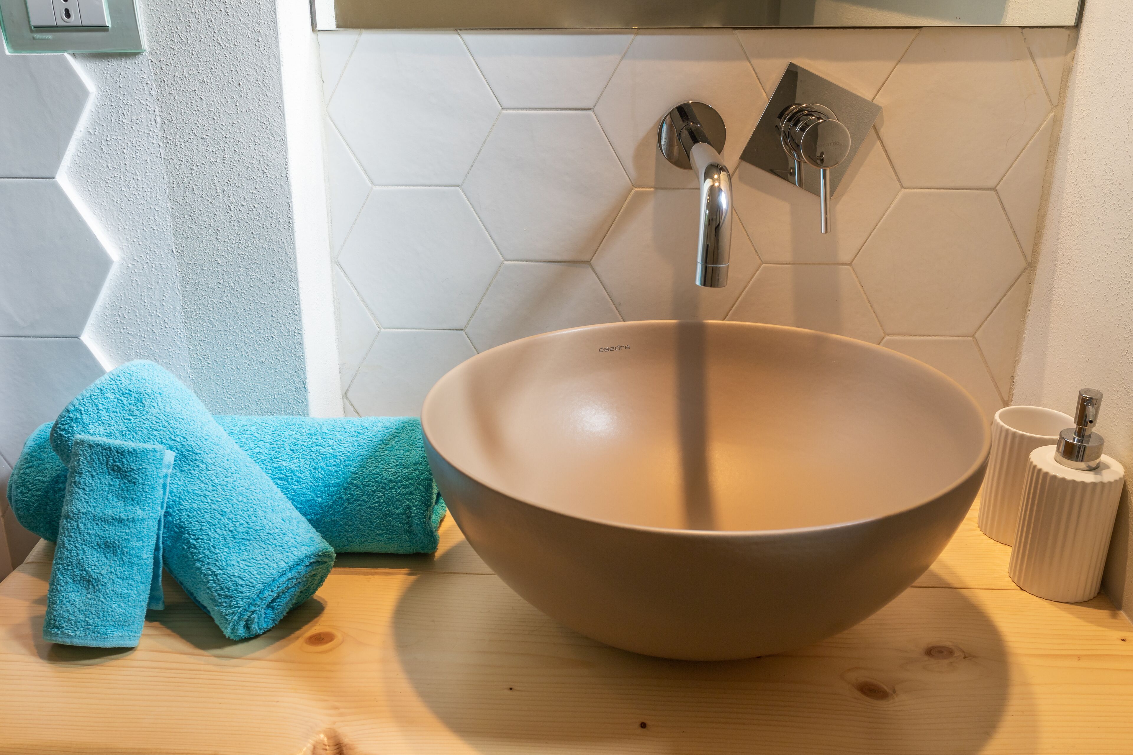 Ett badrum med ett beige handfat, en handduk och en tvåldispenser.