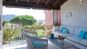 A balcony with wicker furniture, a sofa, and a table with a vase of flowers.