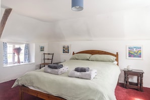 A bedroom with a bed, a window with curtains, a chair, and artwork on the walls. - Gorgeous thatched cottage in Purbeck - ideal for family holidays (Bere Regis)