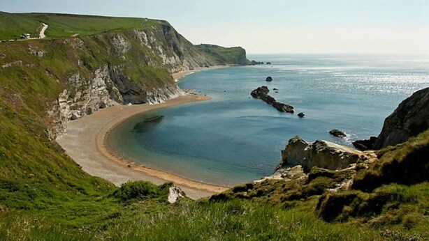 A coastal landscape with a curved sandy beach, rocky outcrops, and grassy cliffs. - Gorgeous thatched cottage in Purbeck - ideal for family holidays (Bere Regis)