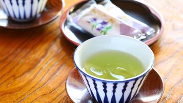 A wooden table with two cups of green tea and a plate with a wrapped item.