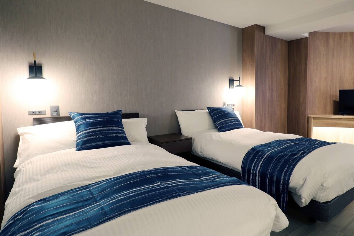 Habitació d'hotel amb dos llits, televisió i escriptori.