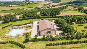 Ein Steinhäuschen mit Swimmingpool, umgeben von üppiger Vegetation und Weinbergen.