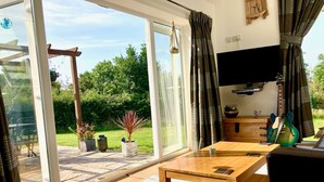 A modern living room with a large sliding glass door leading to a patio area. - Kokopelli cottage near the Donkey sanctuary Sidmouth , modern and pet friendly. (Sidmouth)