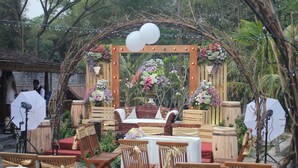 Decoración para una boda al aire libre con un arco de madera, arreglos florales y asientos.