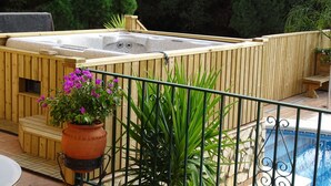 Un jacuzzi con muelle de madera, pared de piedra y piscina.