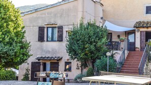 A courtyard with a table and chairs, a staircase, and a building with a balcony.