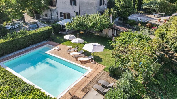 A villa with a swimming pool, outdoor seating, and a garden.