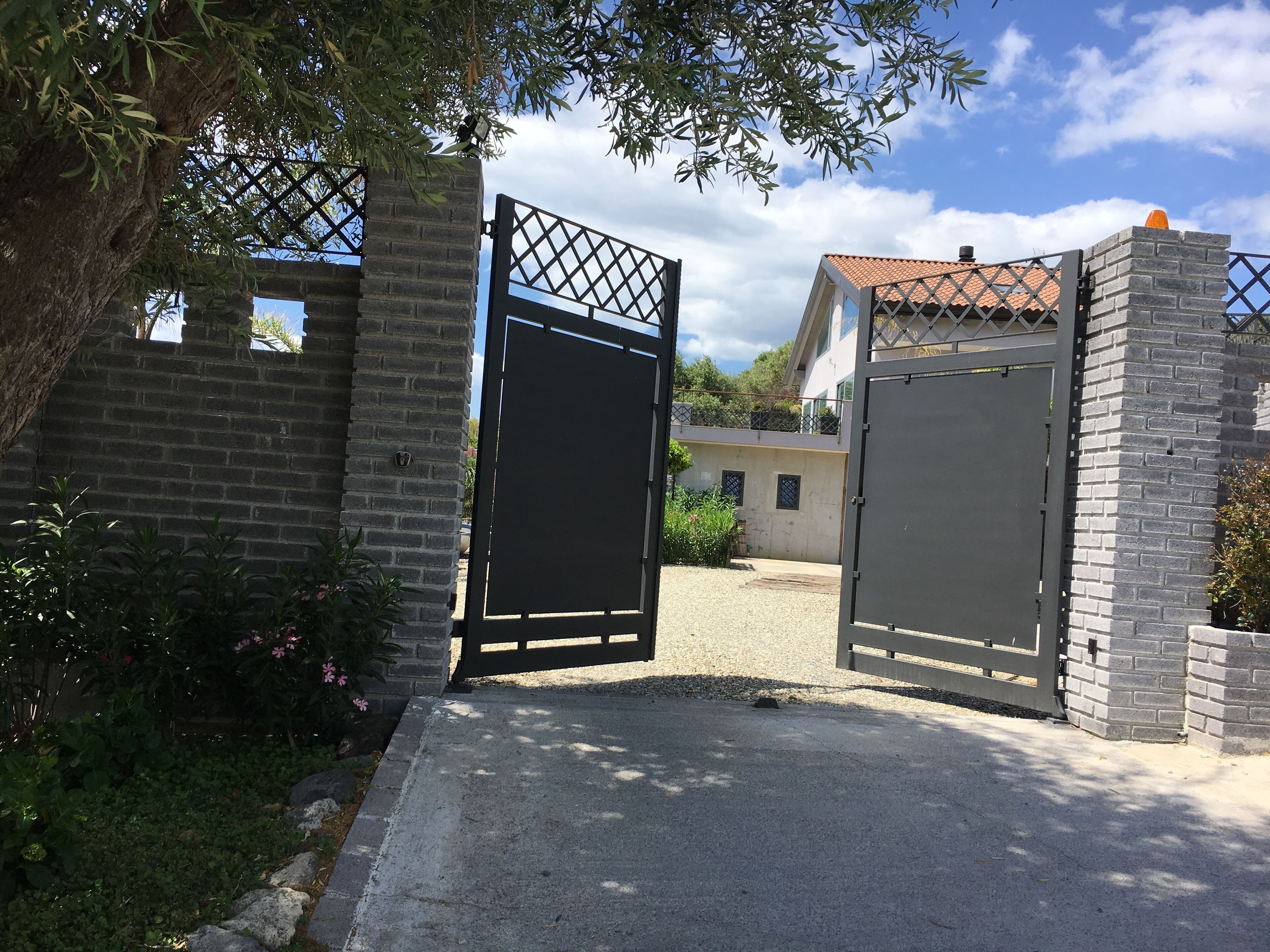 A gated entrance with a brick wall and a metal gate.