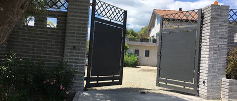 A gated entrance with a brick wall and a metal gate.