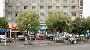 A multi-story building with a prominent red and white sign at the top. - OYO 8027 Li Hu Business Hotel (Shenzhen)