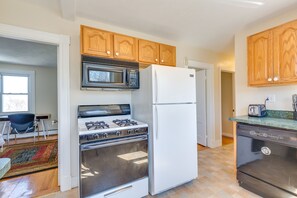 A kitchen with wooden cabinets, a microwave, a stove, a refrigerator, and a dishwasher. - Chestnut Hill Apts by Starlight Suites (Brookline)