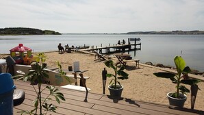 A beachside area with a wooden deck, picnic tables, and potted plants. - Apartment 2 - Ahoi-Marie (Middelhagen)
