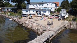 A lakeside property with a dock, outdoor seating, and a large house. - Apartment 2 - Ahoi-Marie (Middelhagen)