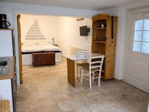 Une petite pièce comprenant un lit, un petit bureau, une chaise et une armoire en bois.