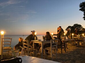 Un restaurant situé en bord de mer, avec une terrasse, des tables, des chaises et une vue sur la mer.