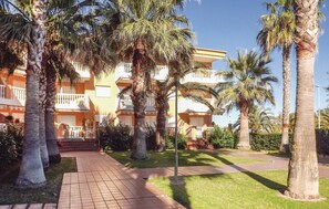 Experience the charm of Mediterranean architecture at this hotel, surrounded by a beautifully maintained garden with palm trees and a paved walkway.