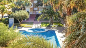 A swimming pool surrounded by palm trees and a building with balconies. - 2 bedroom lovely apartment in Piles (Piles)