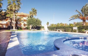 Relax by the serene pool surrounded by lush greenery and palm trees.