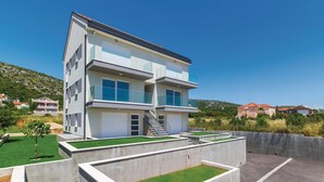 Un moderno edificio de dos plantas con balcones, una escalera y un pequeño jardín.