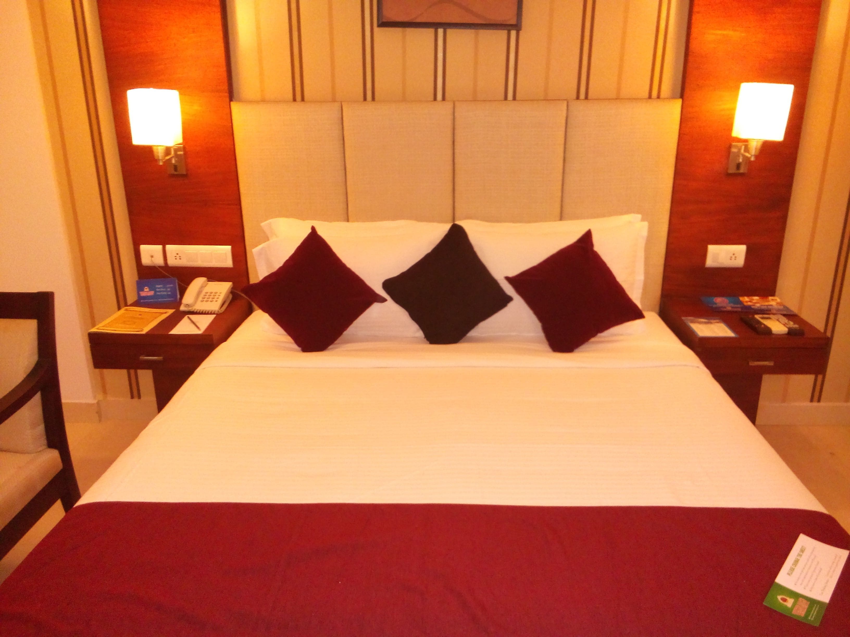 A hotel room with a large bed, two bedside tables, a nightstand, a desk, and a chair.
