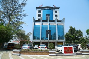 Um hotel moderno com um letreiro chamativo 'White Gate', fachada de vidro e área de estacionamento com vários carros.