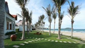 Un resort con un césped bien cuidado, palmeras y vista a la playa.