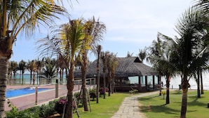 Un resort con piscina, palmeras y un edificio de techo de paja.