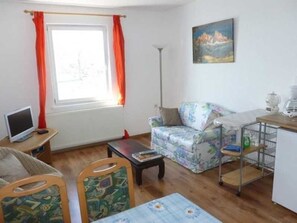 A living room with a sofa, a table, a TV, and a painting on the wall.