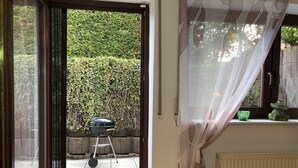 Ein Zimmer mit einer Schiebetür, die auf eine Terrasse mit einem Grill führt.