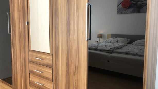 Ein Schlafzimmer mit einem Holzschrank, einem Bett mit floralem Bettbezug und einer Wandlampe.