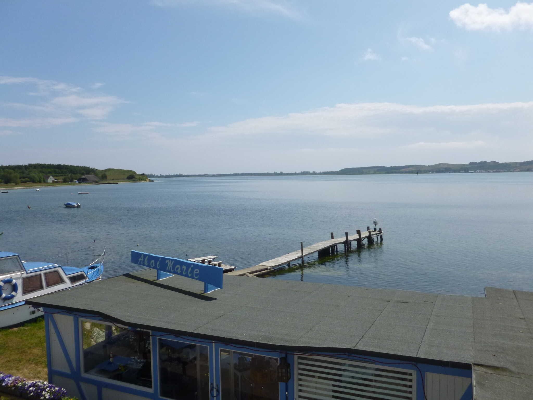 A calm lake with boats, a pier, and a building with a sign reading "Alai Marie".