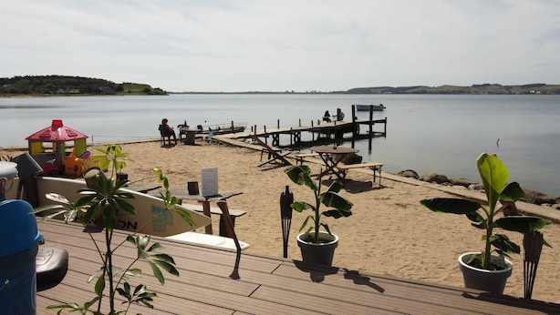 Ein Strandbereich mit Holzterrasse, Picknicktischen und Kübelpflanzen.