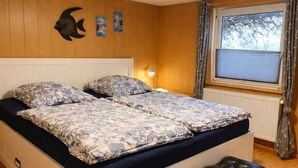 A double bed with floral bedding, a bedside lamp, and a fish decoration on the wall.