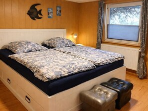 Un letto matrimoniale con biancheria da letto floreale, una lampada da comodino e una decorazione a forma di pesce sul muro.