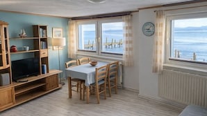 Ein gemütliches Zimmer mit Esstisch, Stühlen, einem Fernseher und einem Bücherregal.