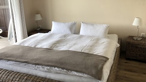 A neatly made bed with white linens, two bedside tables with lamps, and a wooden artwork on the wall. - Sunny 2 room apartment with a fantastic view of Lake Millstatt (Millstatt)