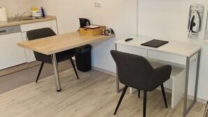 A small kitchenette with a wooden table, two chairs, a coffee maker, and a trash bin. - Apartment-32609de (Hüllhorst)