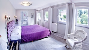 Une chambre à coucher avec un lit, une chaise, une fenêtre et une salle de bain visible au fond.