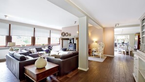 Un salon moderne avec un canapé d’angle, un plancher en bois et une cheminée.