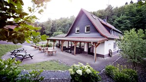 Une maison dotée d’un patio couvert, d’un espace salon extérieur et d’un jardin.