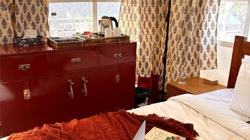 A bedroom with a red dresser, a bed with a red blanket, and a laptop on the bed.