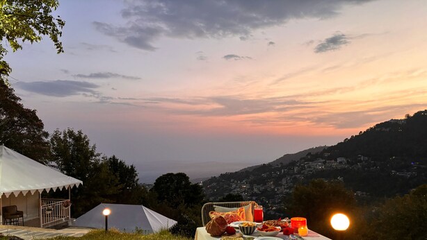 A dining table set outdoors with a view of a cityscape at sunset.
