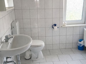 A bathroom with a white sink, toilet, and a window.