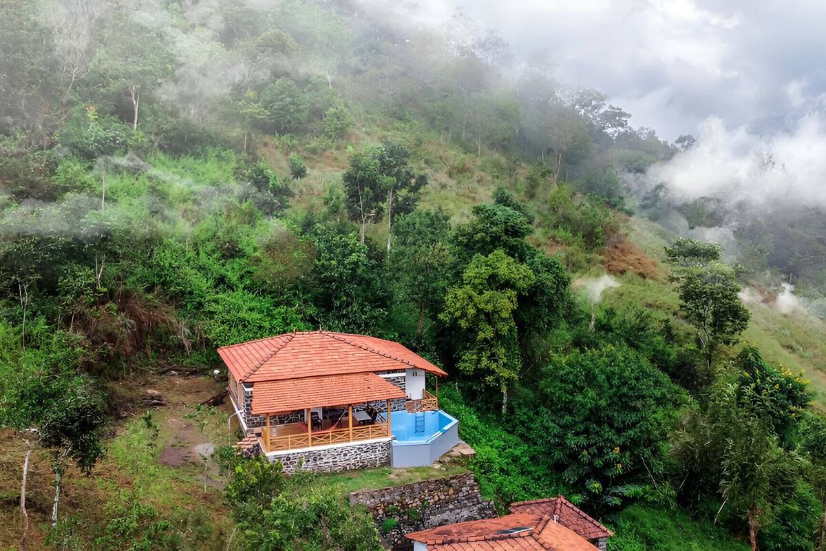 Ein Haus mit rotem Dach, einem Swimmingpool, umgeben von üppiger Vegetation und Hügeln.