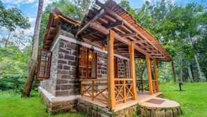 A rustic cabin with a stone exterior, wooden porch, and a small deck area.
