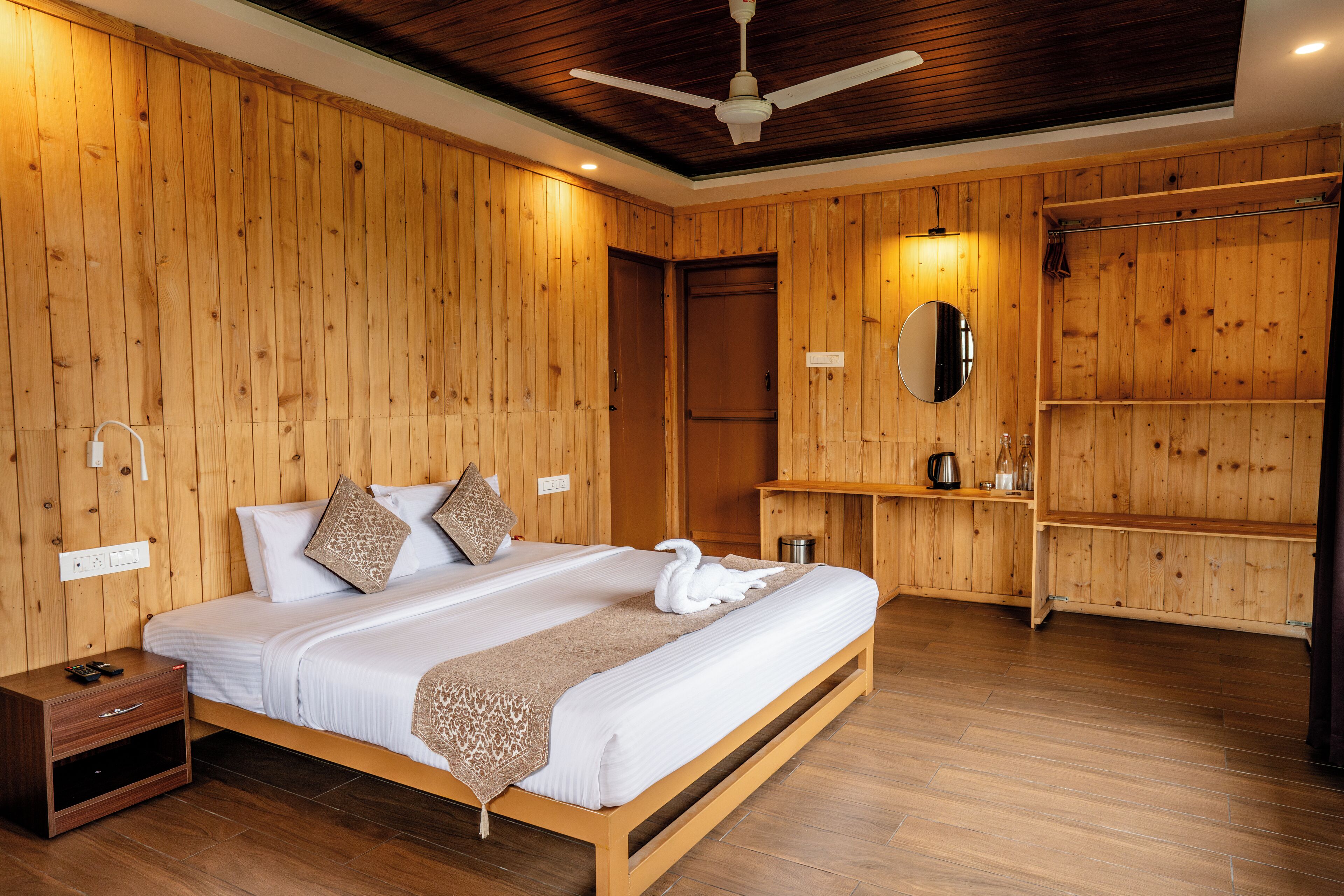 Una camera da letto con rivestimenti in legno, un letto, comodini, uno specchio e una ventola a soffitto.